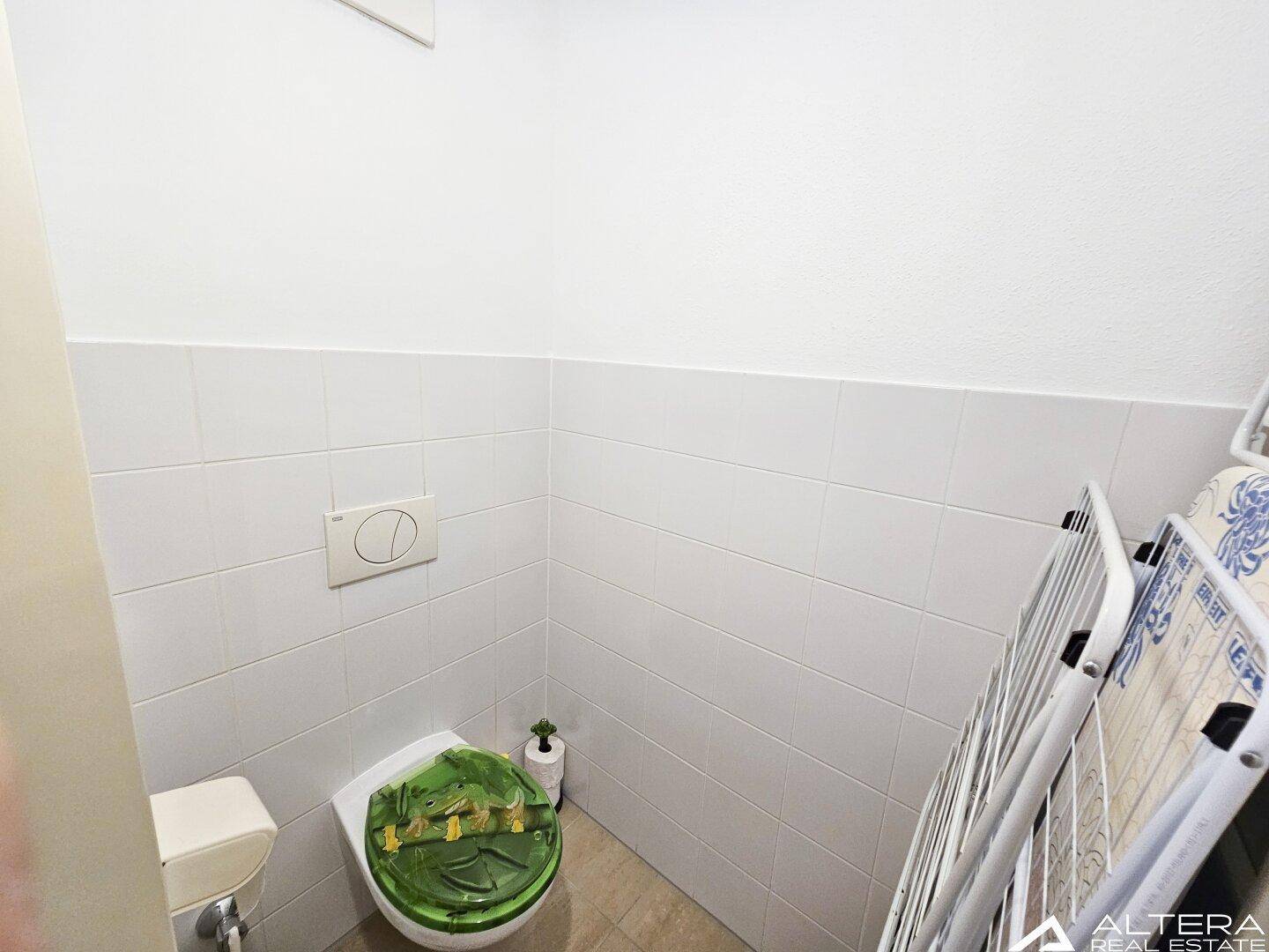 Kleines separates WC mit weißen Fliesen und einer Toilette.
