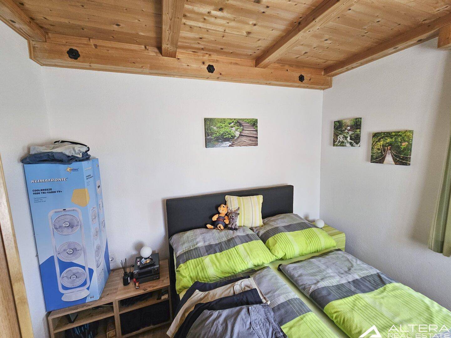 Schlafzimmer mit Doppelbett, Holzbalkendecke und einfacher Einrichtung, hell und funktional.