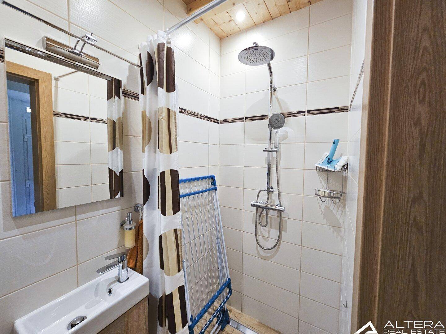 Modernes Badezimmer mit Duschkabine, Einzelwaschbecken und hellen Fliesen, funktional und sauber.