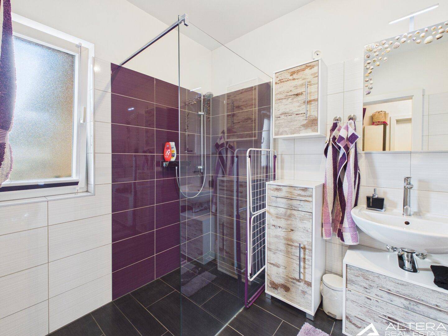 Modernes Badezimmer mit ebenerdiger Dusche, Einzelwaschbecken und farbigen Akzentfliesen, hell und funktional.