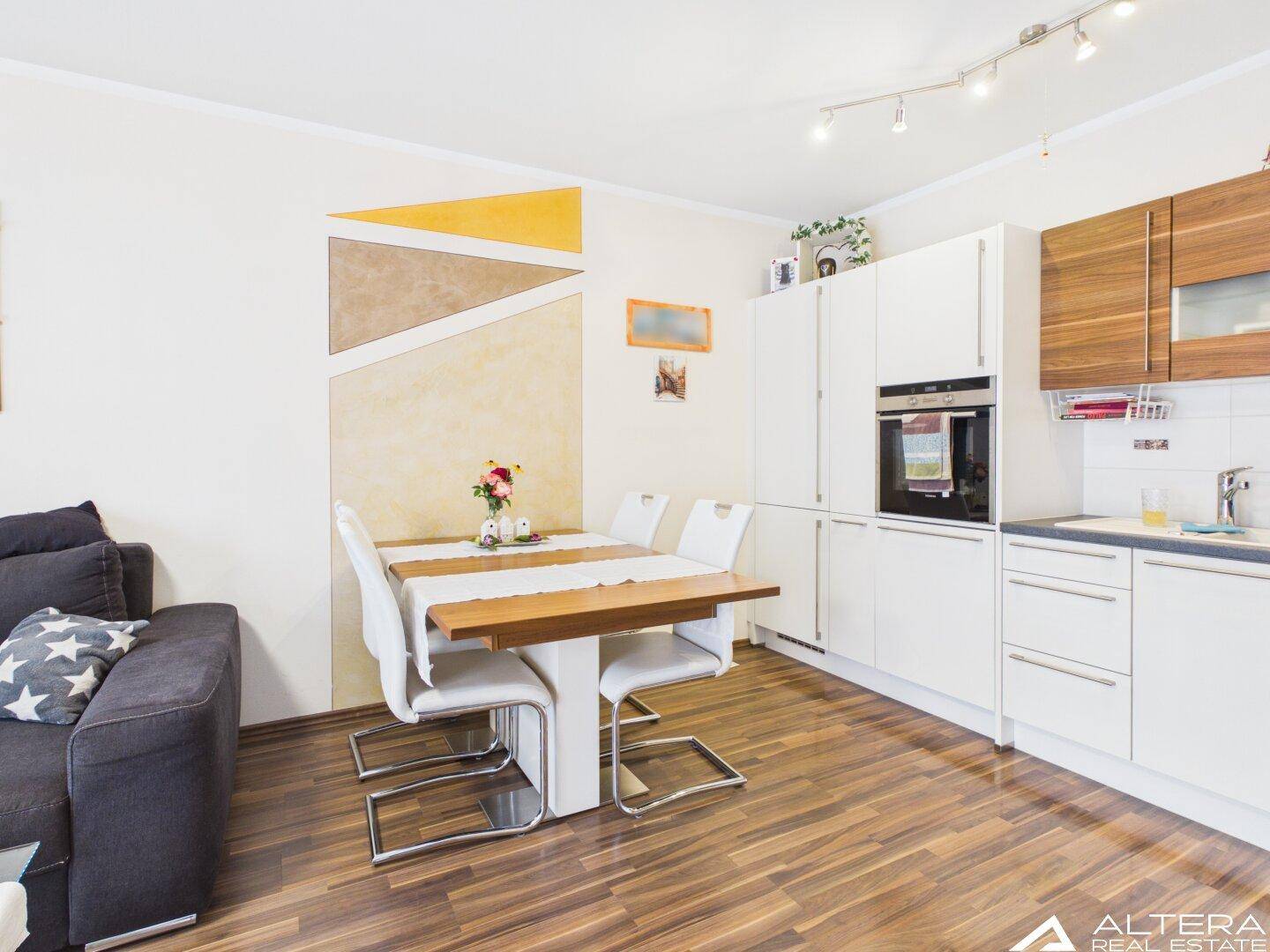 Moderne Einbauküche mit Essbereich, weißen Fronten und Holzdetails, ideal für gesellige Kochabende.