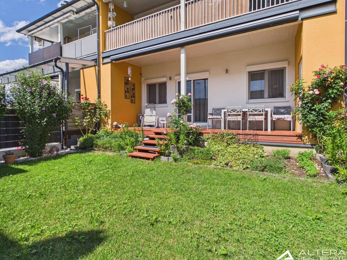 Weitläufige Terrasse mit Zugang zum Garten, ideal für Entspannung im Freien und umgeben von Grün.