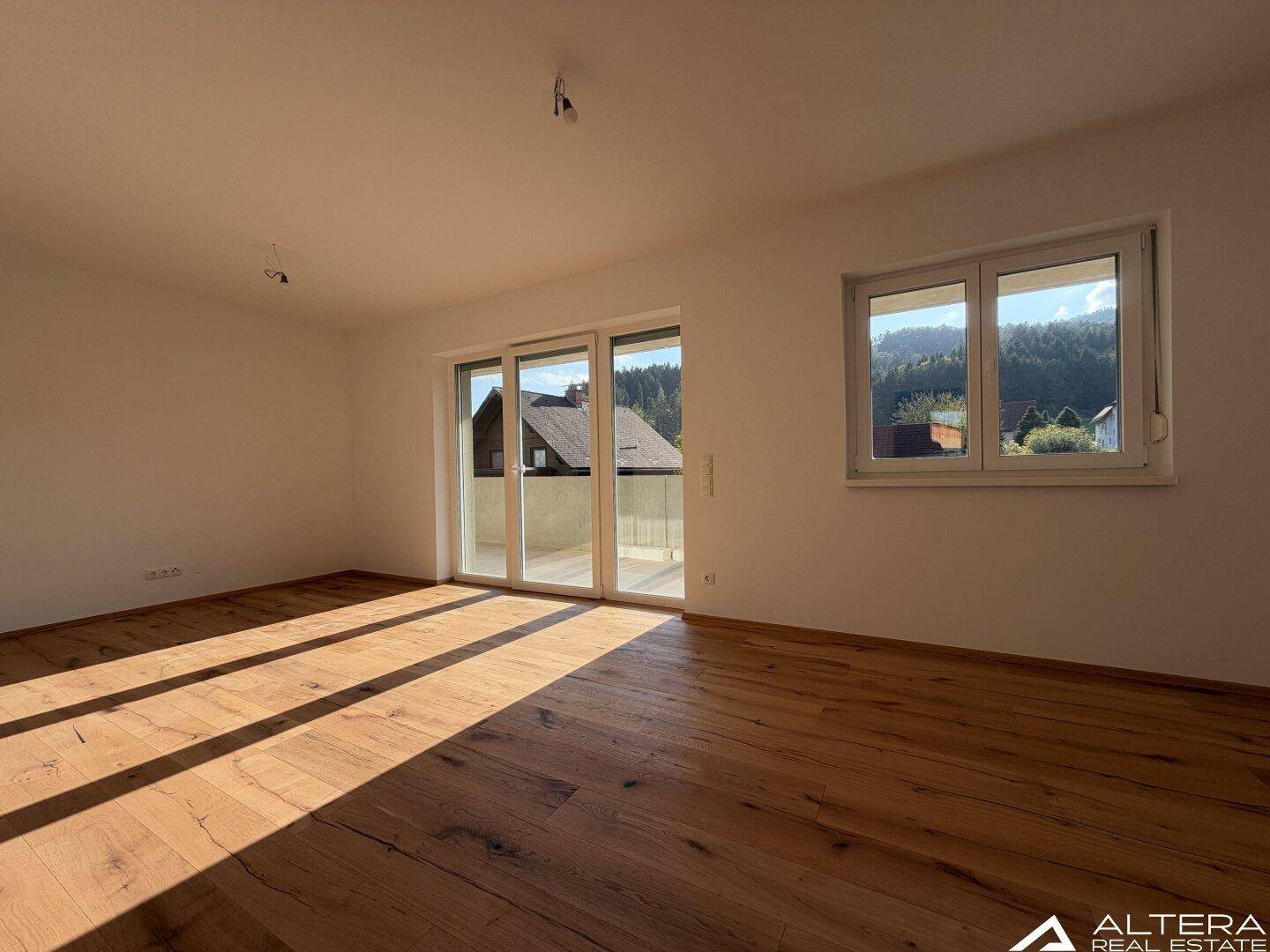 Lichtdurchflutetes Wohnzimmer mit Holzboden und Blick auf die umliegende Landschaft.
