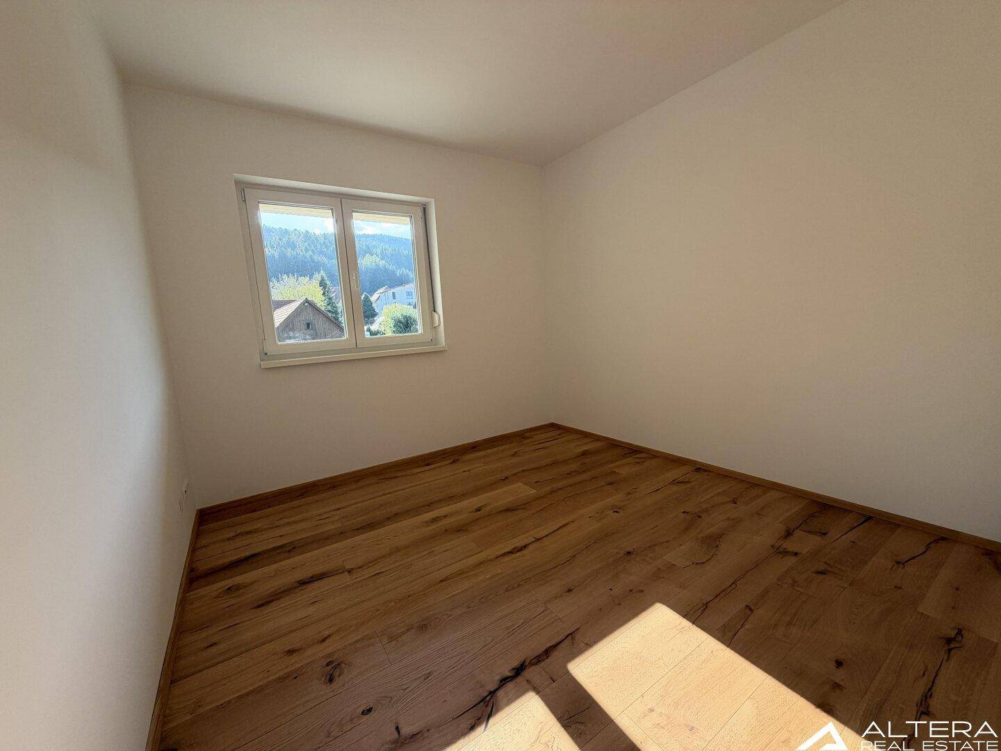 Schlafzimmer mit Holzboden und Fenster, das einen weiten Blick auf die Landschaft ermöglicht.