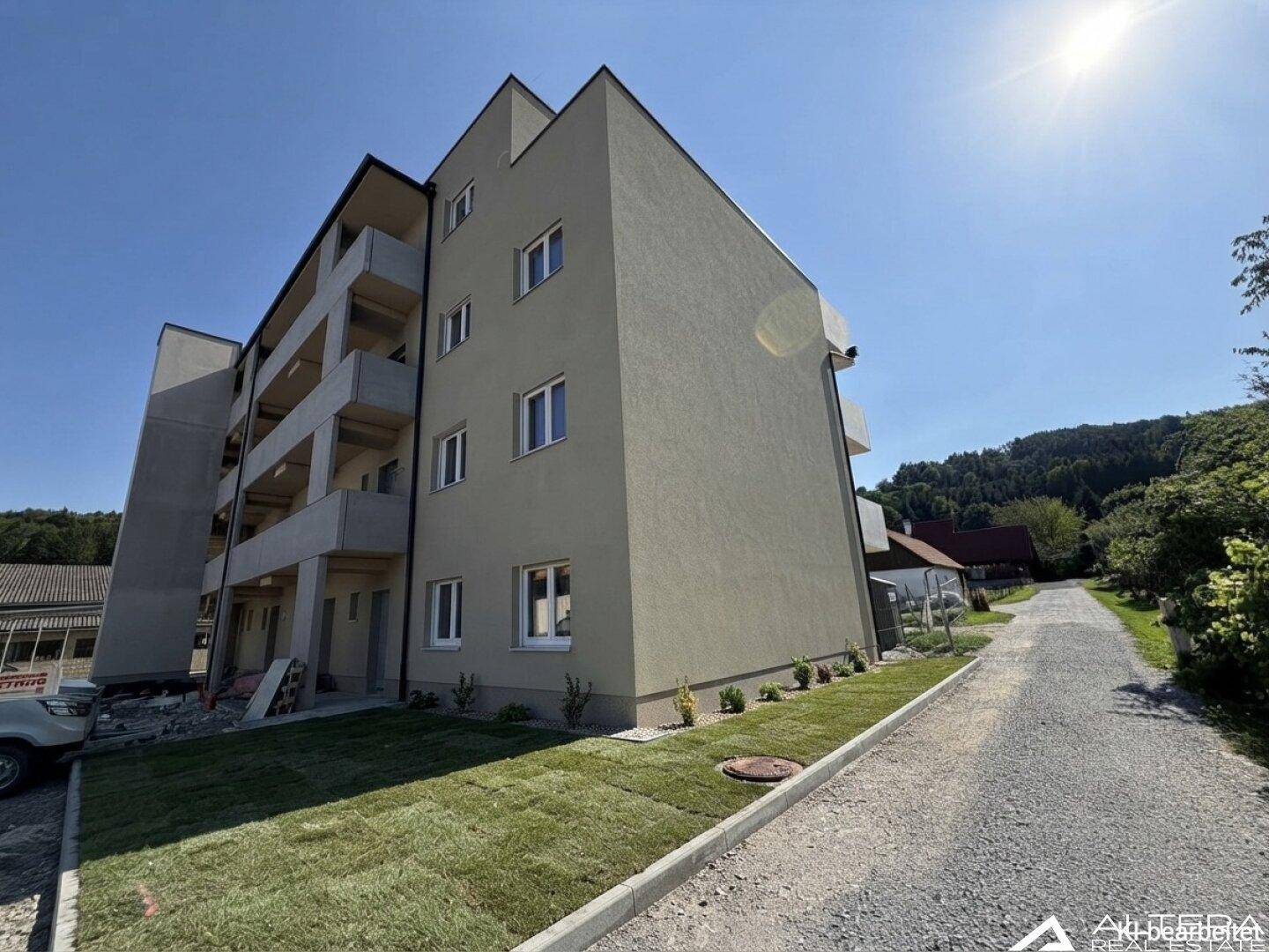 Modernes Mehrfamilienhaus mit Balkonen und gepflegter Grünfläche im Vordergrund.