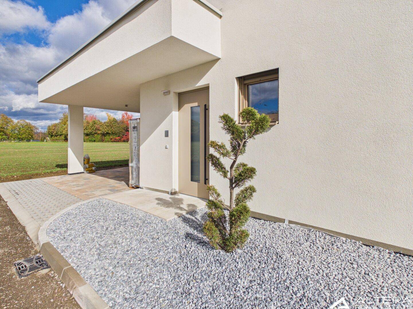 Eingangsbereich des Hauses mit Carport und dekorativem Kiesbeet.