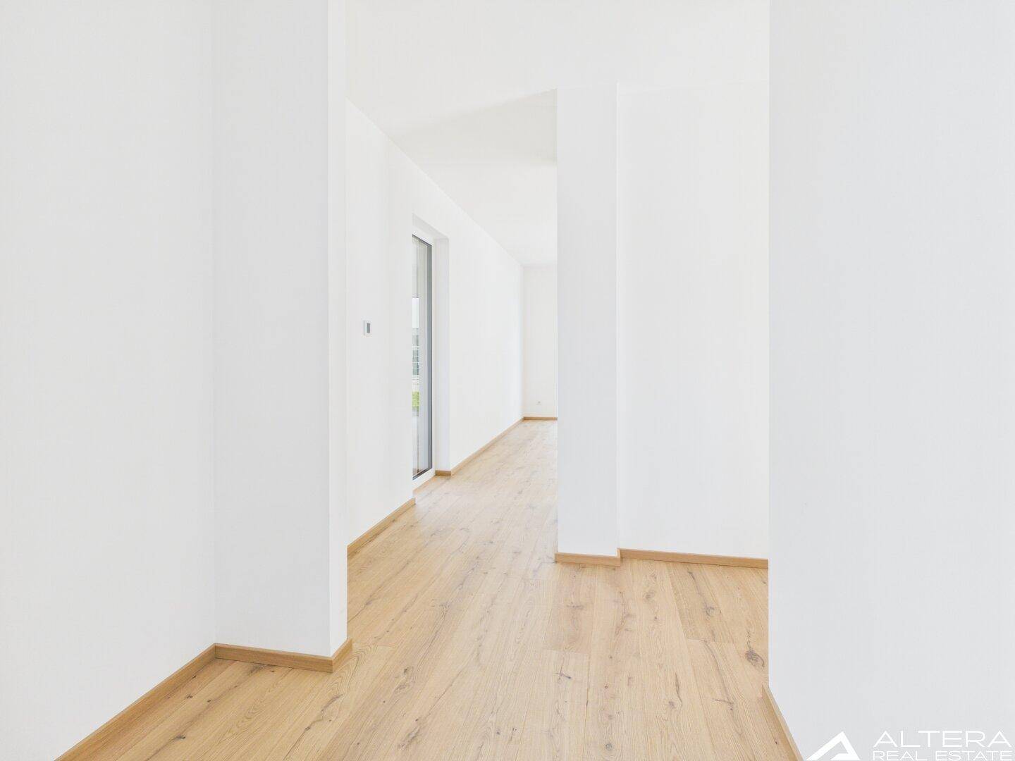 Heller Flur mit modernem Holzboden und weiß gestrichenen Wänden.