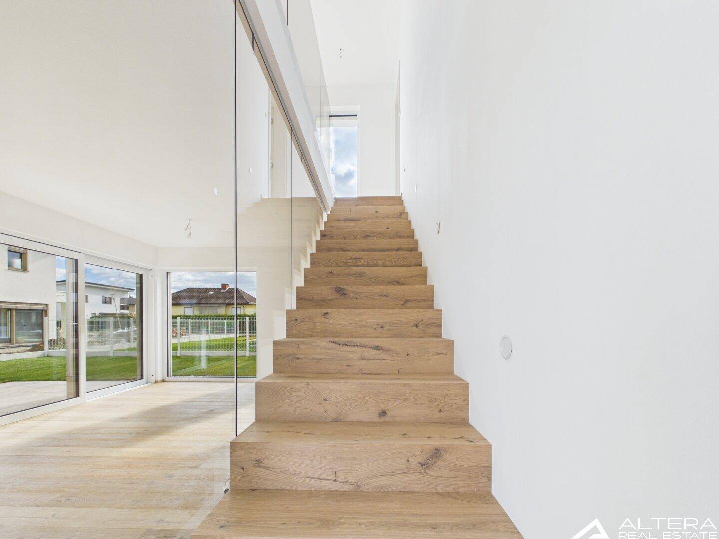 Moderne Holztreppe mit Glasgeländer, die zu den oberen Etagen führt.