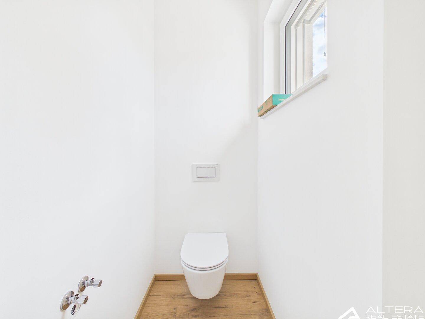 Modernes Gäste-WC mit wandhängender Toilette und kleinem Fenster.