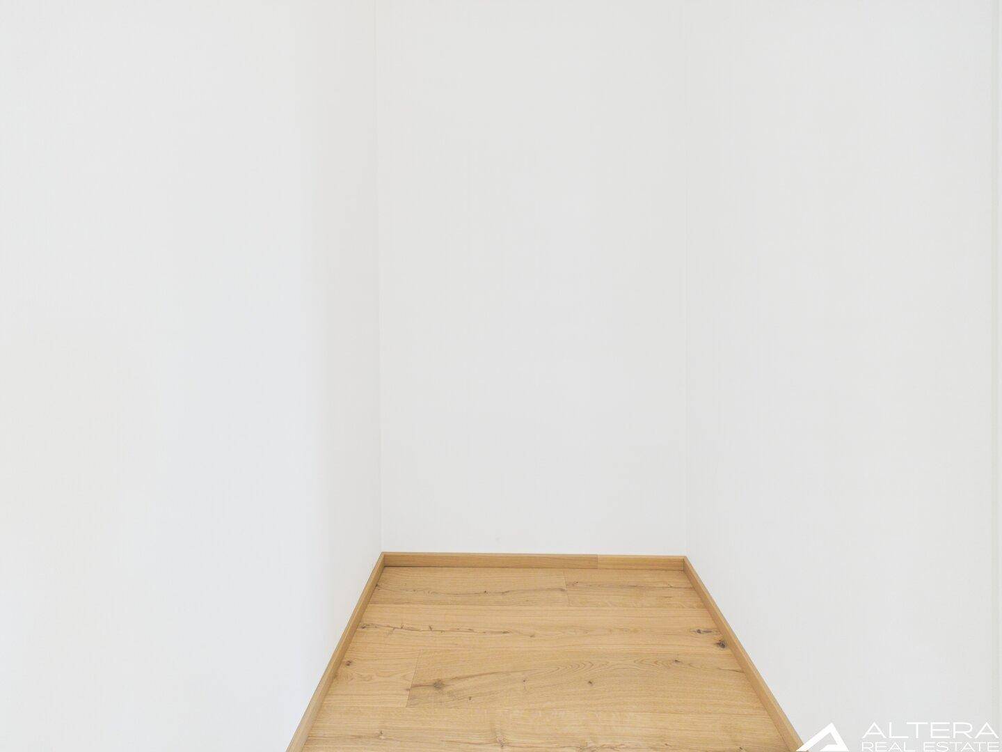 Kleiner, leerer Raum mit Holzboden, ideal als Abstellraum oder Speisekammer.