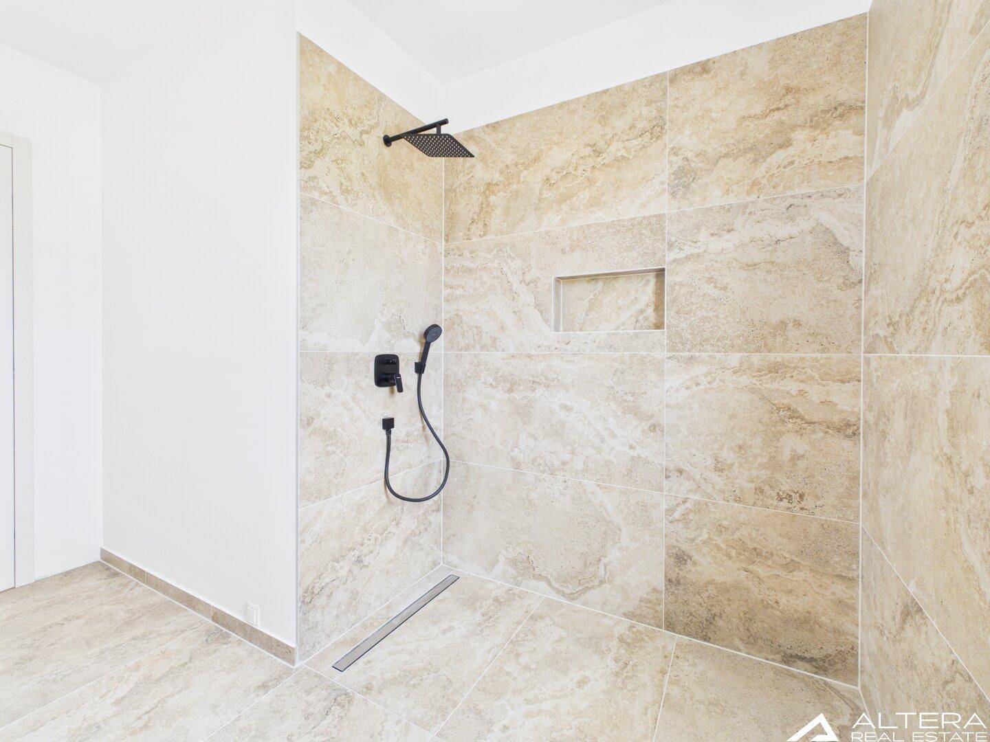 Modernes Badezimmer mit begehbarer Dusche, beigefarbenen Fliesen und schwarzer Armatur.
