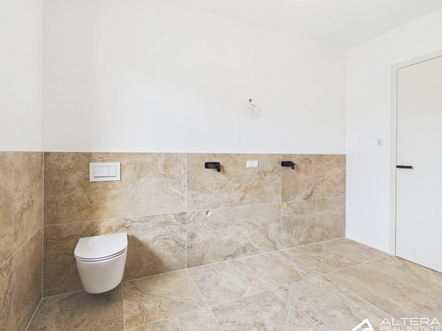 Helles WC mit wandhängender Toilette und beigefarbenen Fliesen, bereit für die Installation.