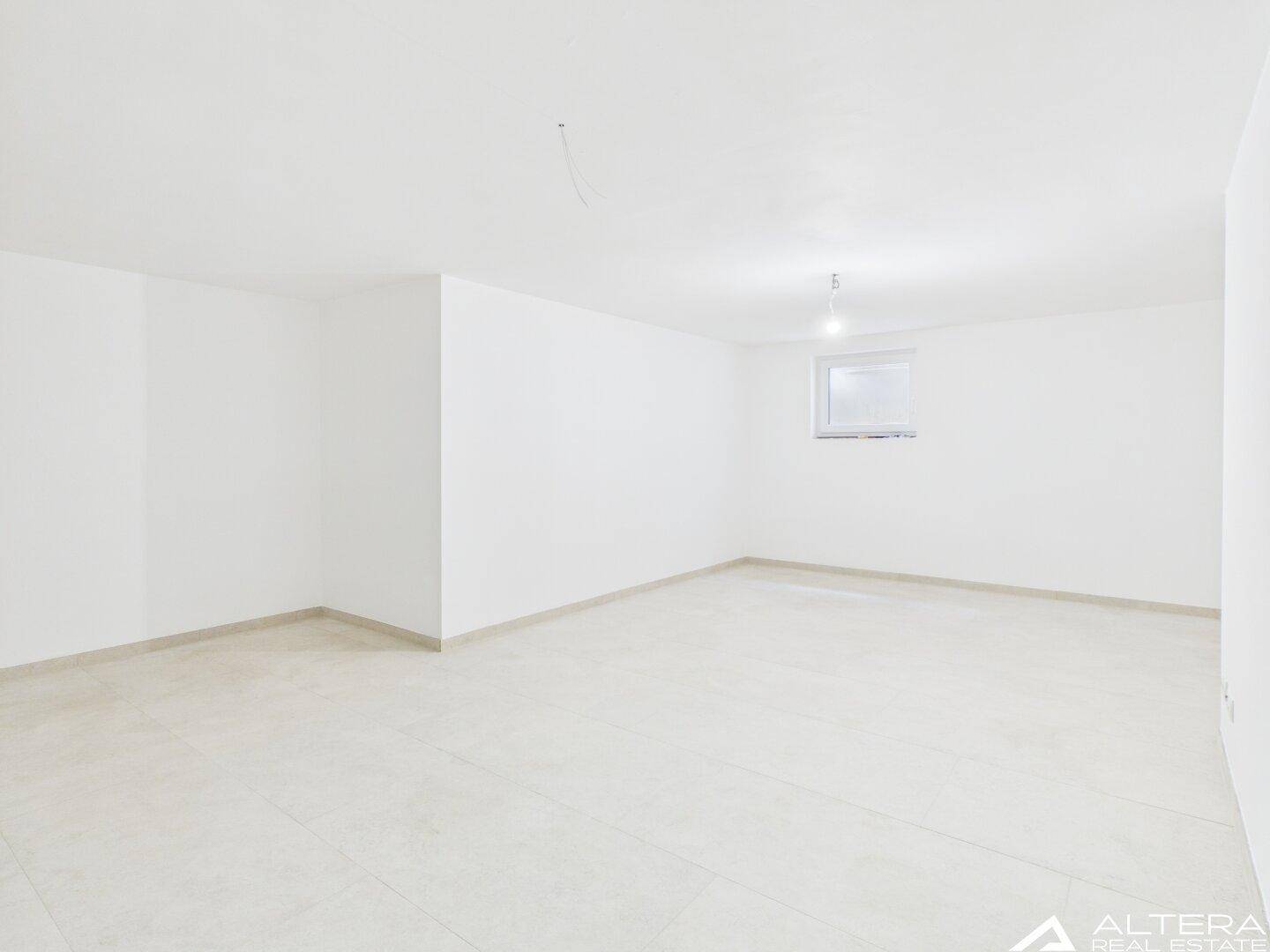 Leerer, heller Raum mit weiß gestrichenen Wänden und einem kleinen Fenster.