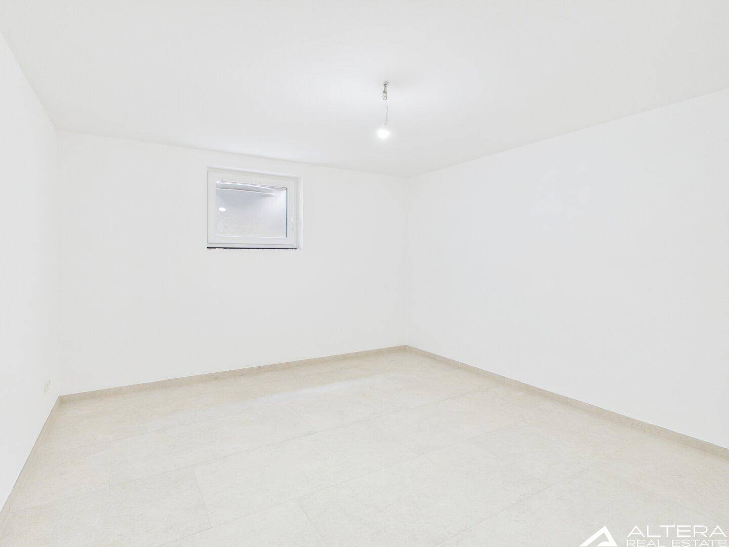 Heller, unmöblierter Raum mit weiß gestrichenen Wänden und einem einzelnen Fenster.