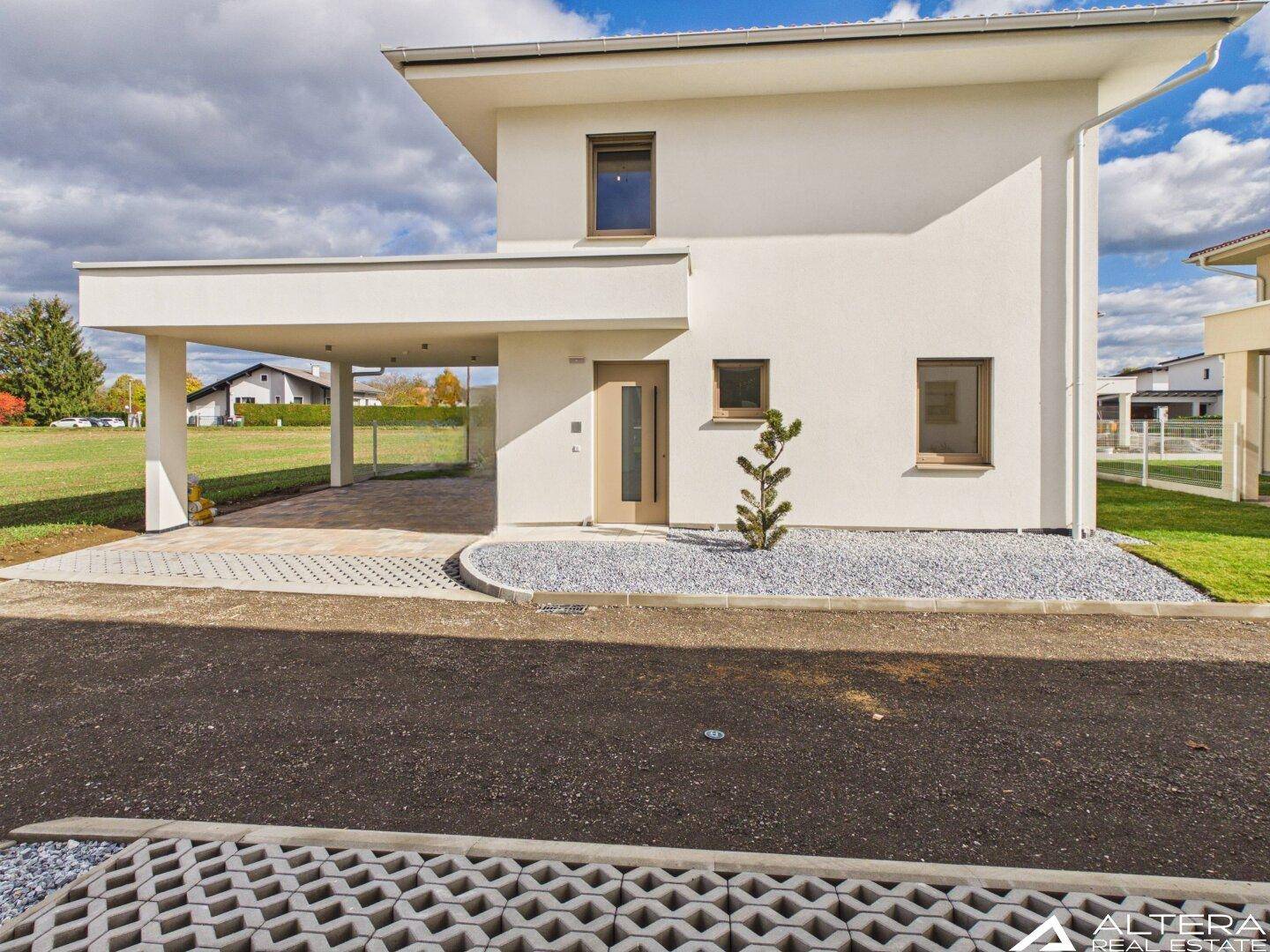 Vorderansicht eines modernen Einfamilienhauses mit Carport und Eingangsbereich.