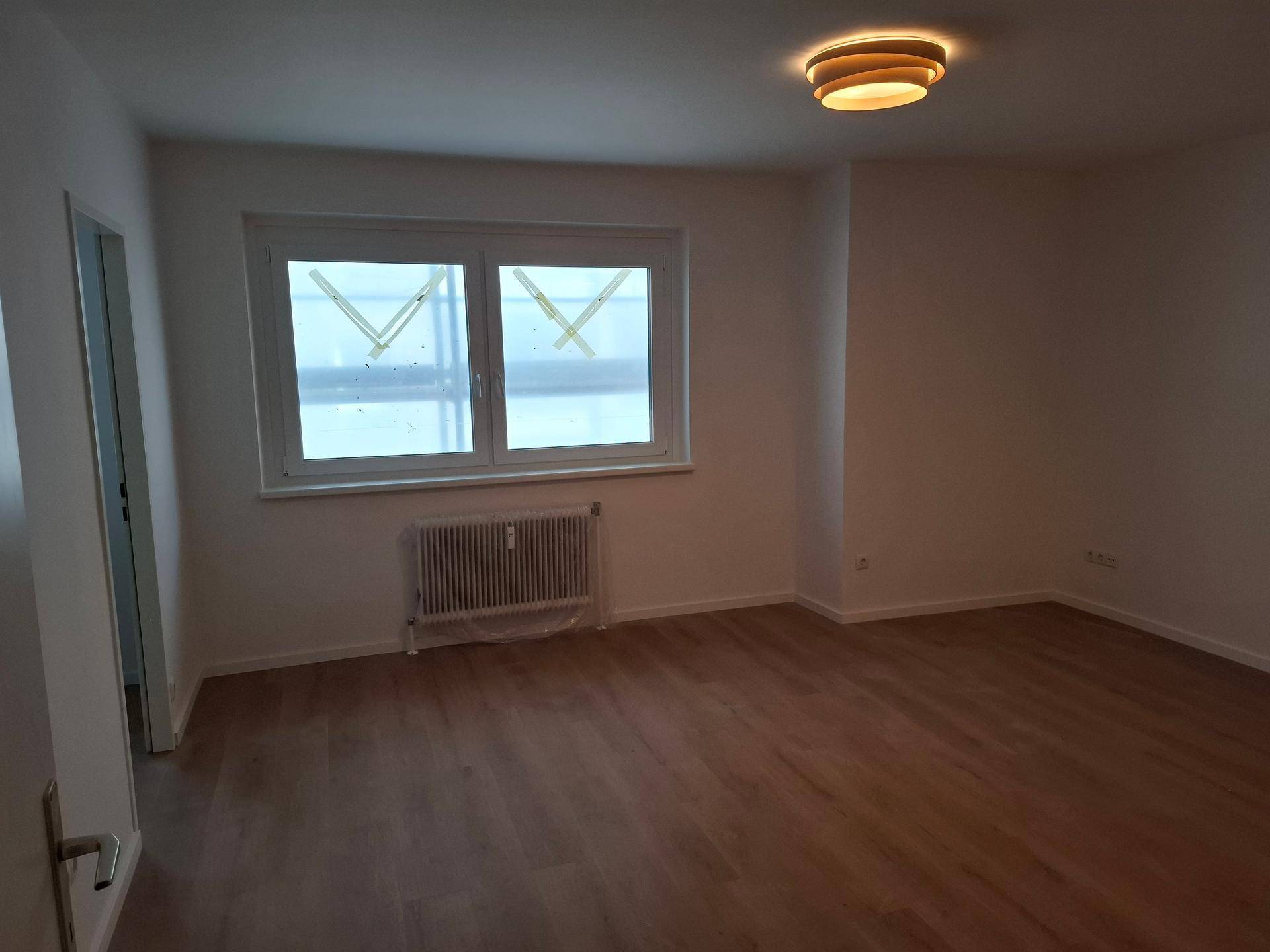 Geräumiger, unmöblierter Raum mit Laminatboden und Fenster, ideal für Wohn- oder Schlafzimmer.