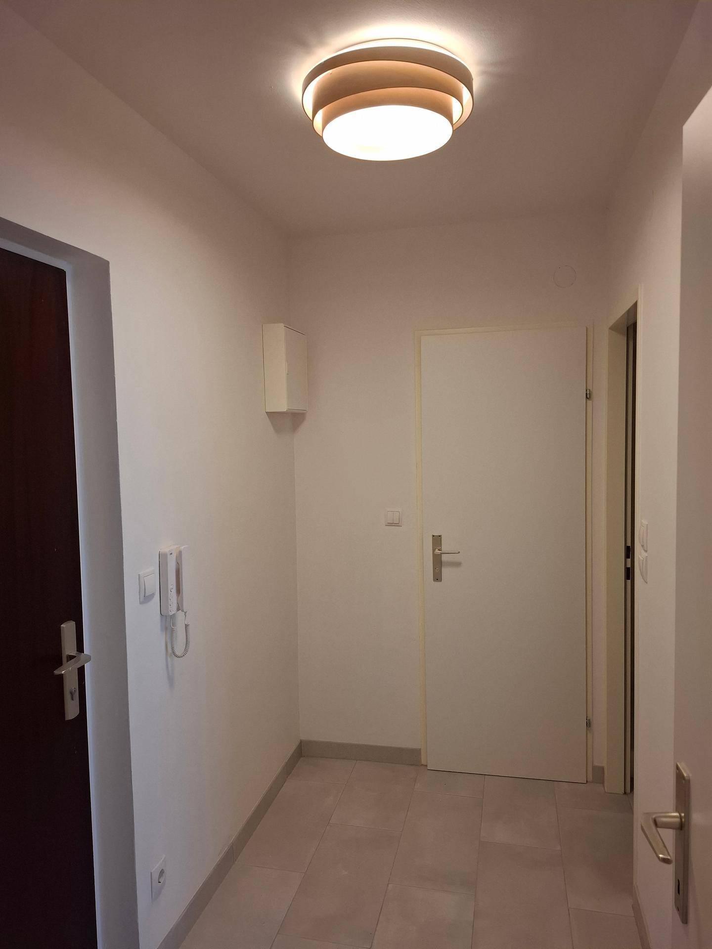 Heller Flur mit Fliesenboden und Gegensprechanlage, verbindet die verschiedenen Räume der Wohnung.