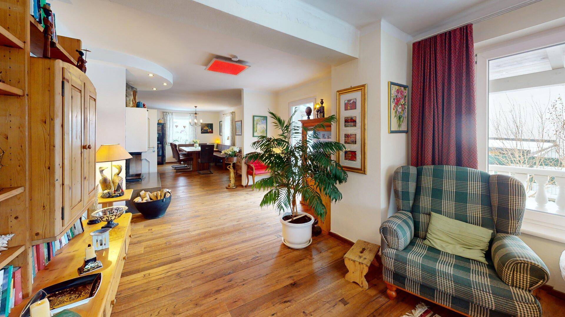 Weitläufiges Wohnzimmer mit Holzboden, bequemen Sitzgelegenheiten und Blick in den Essbereich.