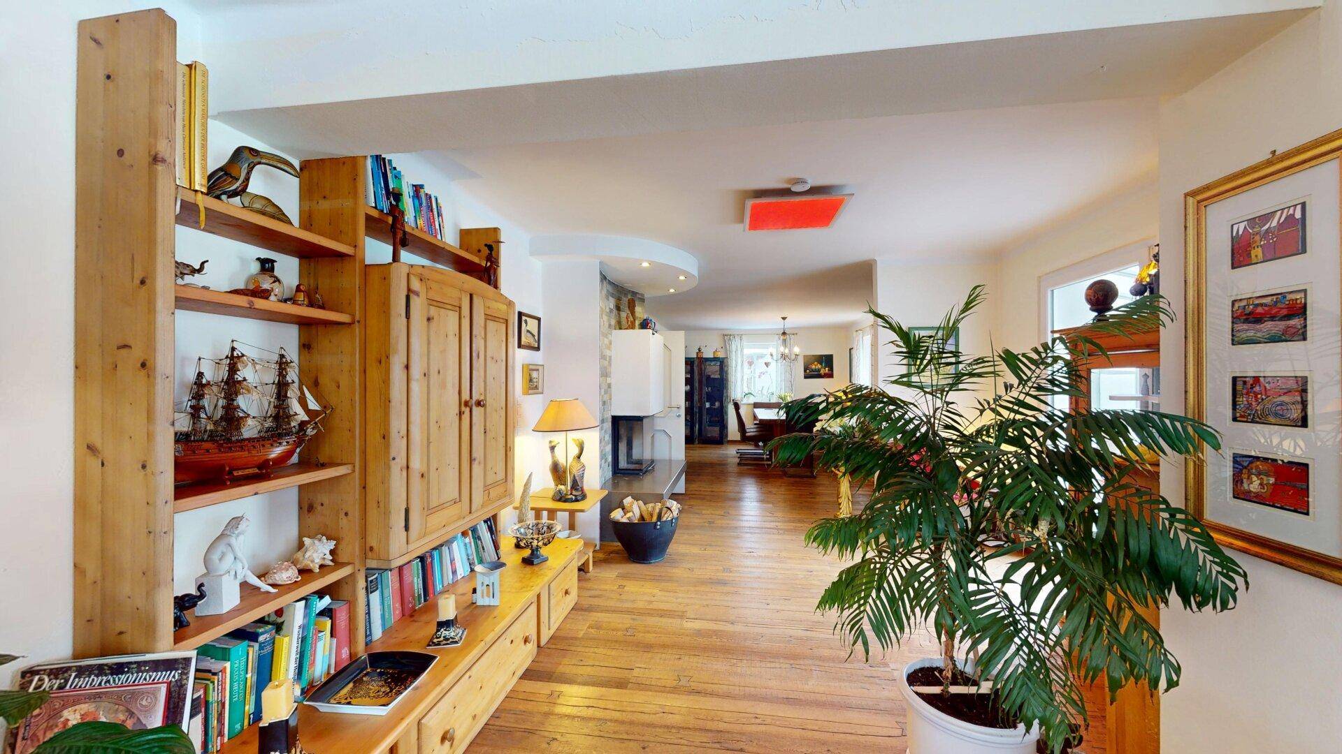 Helles Wohnzimmer mit umfangreichen Bücherregalen, Holzboden und Pflanzen.
