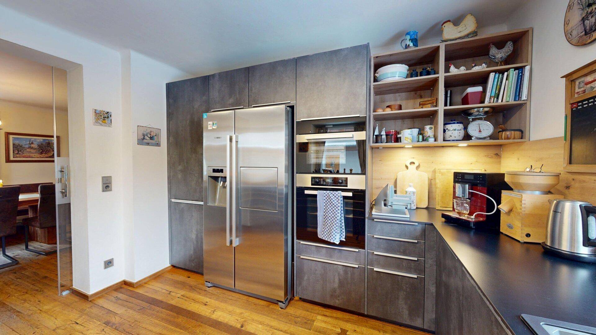 Funktionale Küche mit großem Kühlschrank, Backofen und praktischen offenen Regalen.