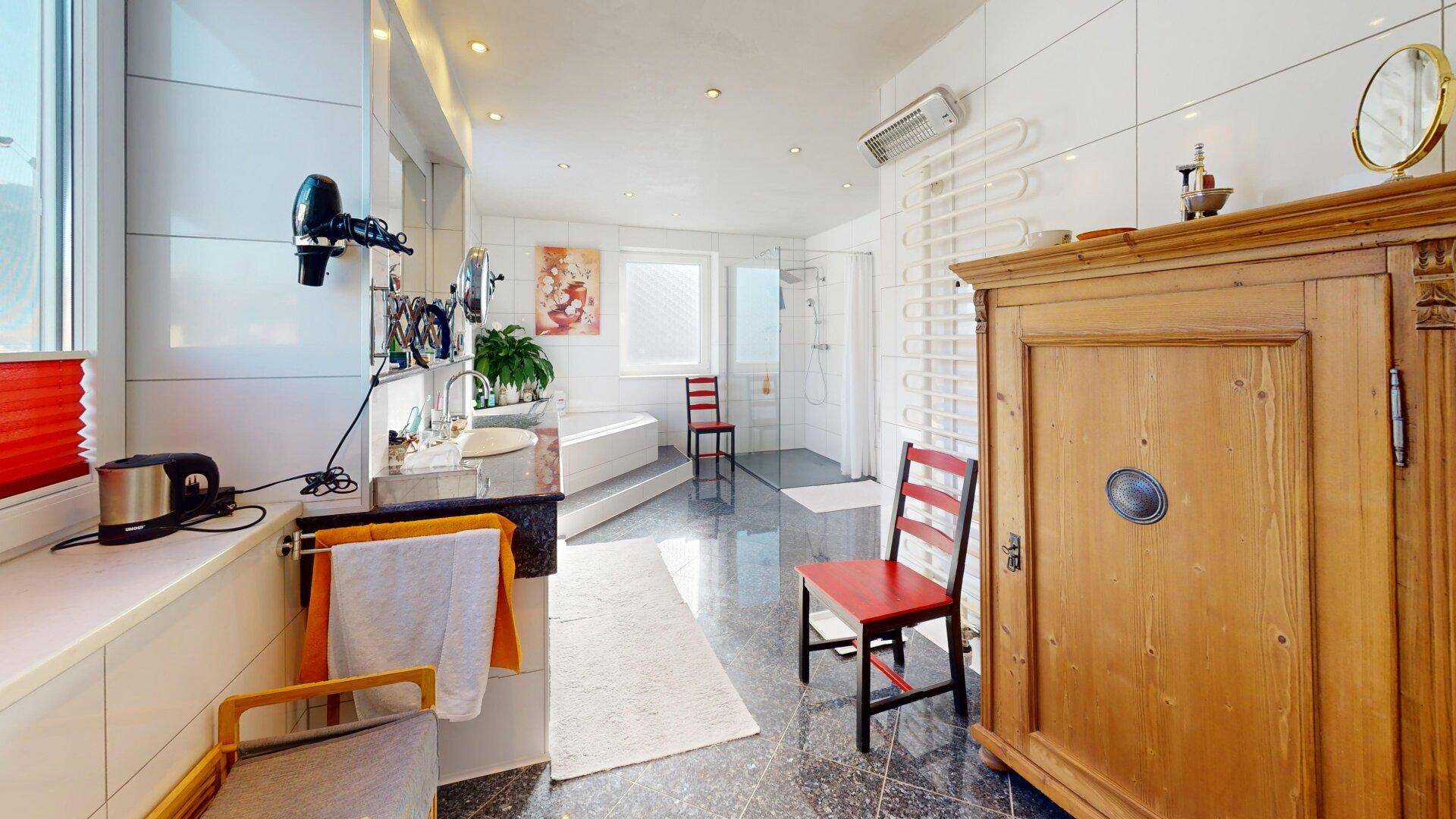 Großes Badezimmer mit Badewanne, Dusche, Doppelwaschbecken und Fenster.