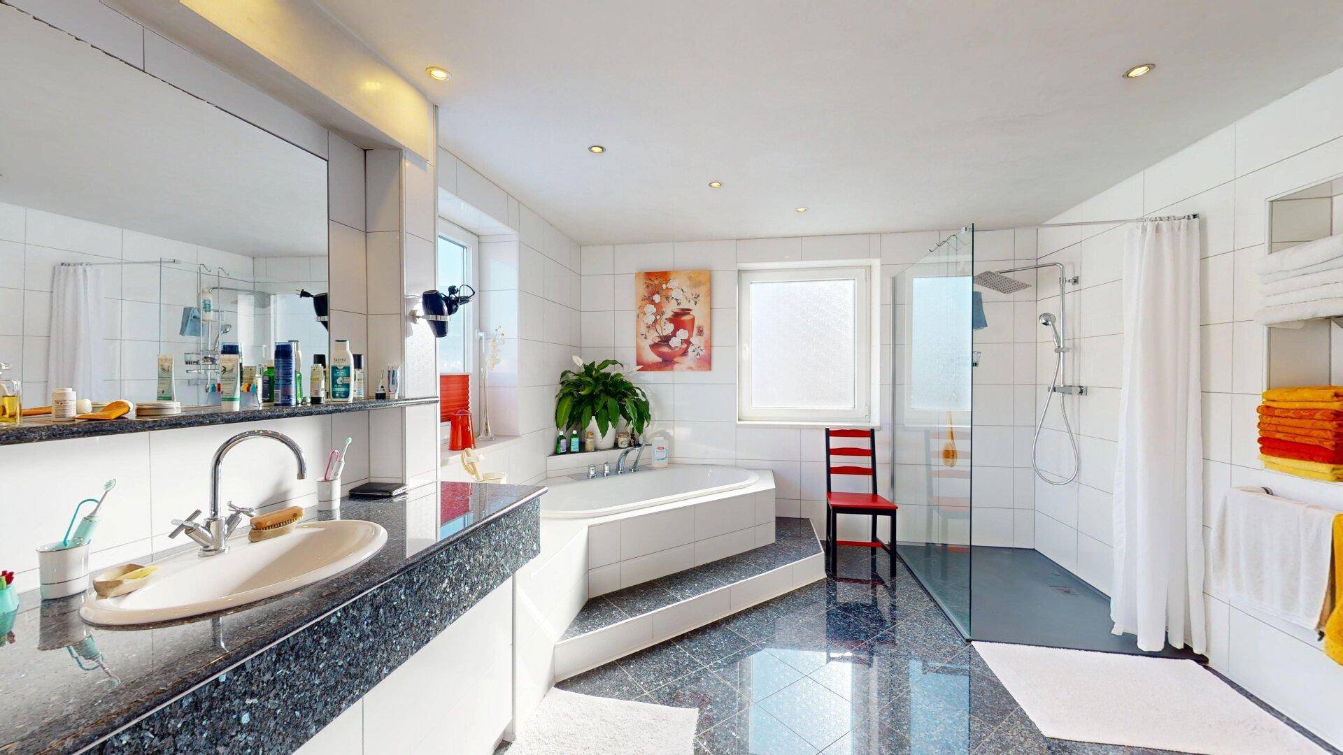 Modernes Badezimmer mit großer Dusche, Badewanne und eleganten Fliesen.
