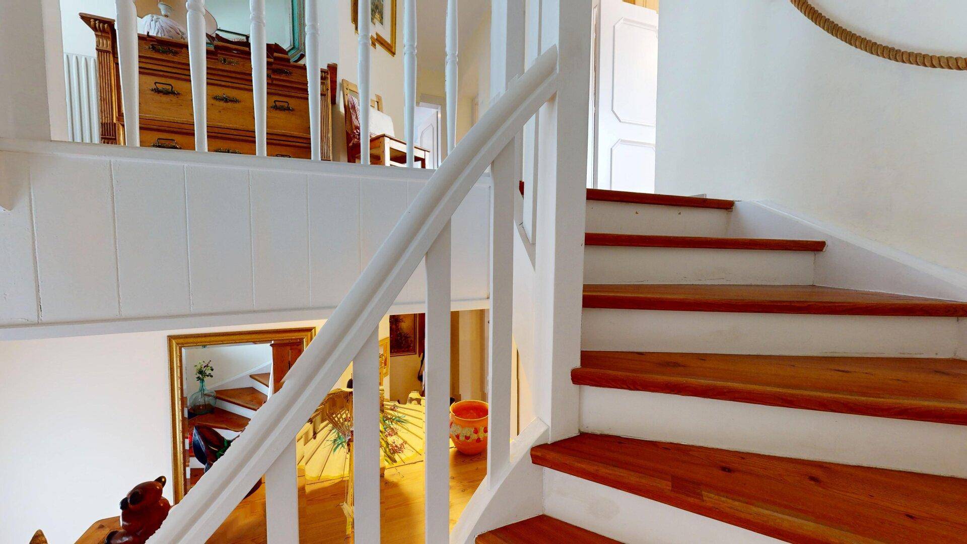 Detailansicht der Holztreppe mit weißem Geländer und traditioneller Gestaltung.