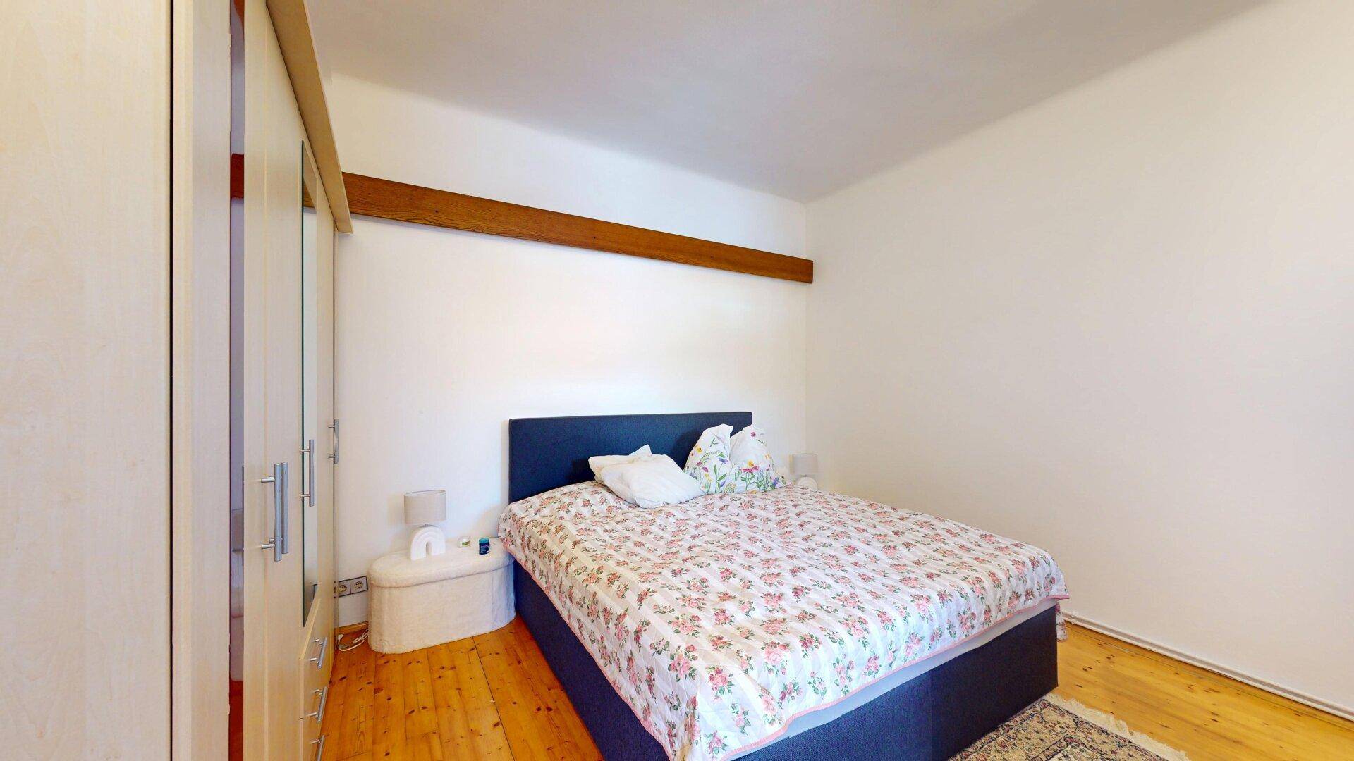 Schlafzimmer mit Holzboden, Doppelbett und großem Kleiderschrank, hell und funktional eingerichtet.