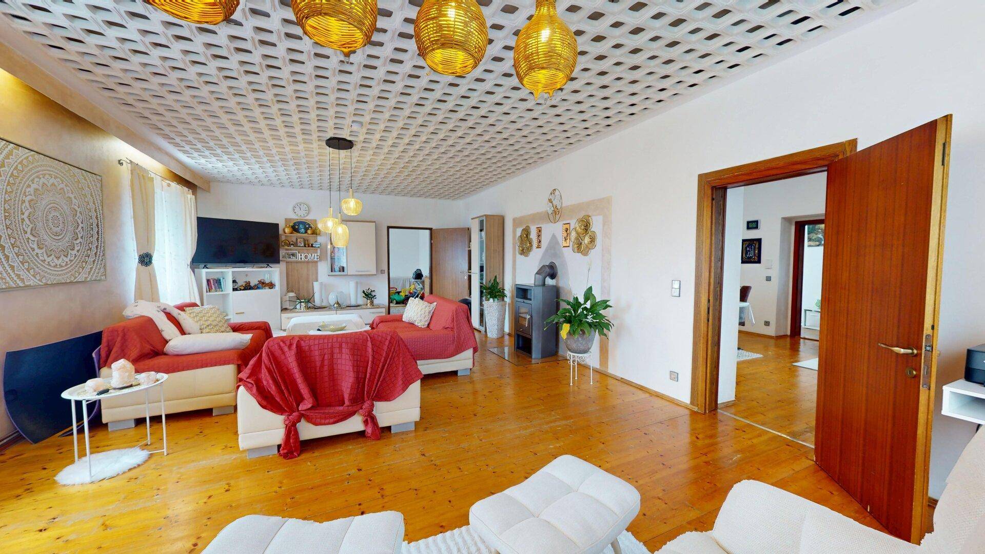 Helles Wohnzimmer mit Holzboden, Kaminofen und dekorativer Deckenverkleidung, einladend gestaltet.