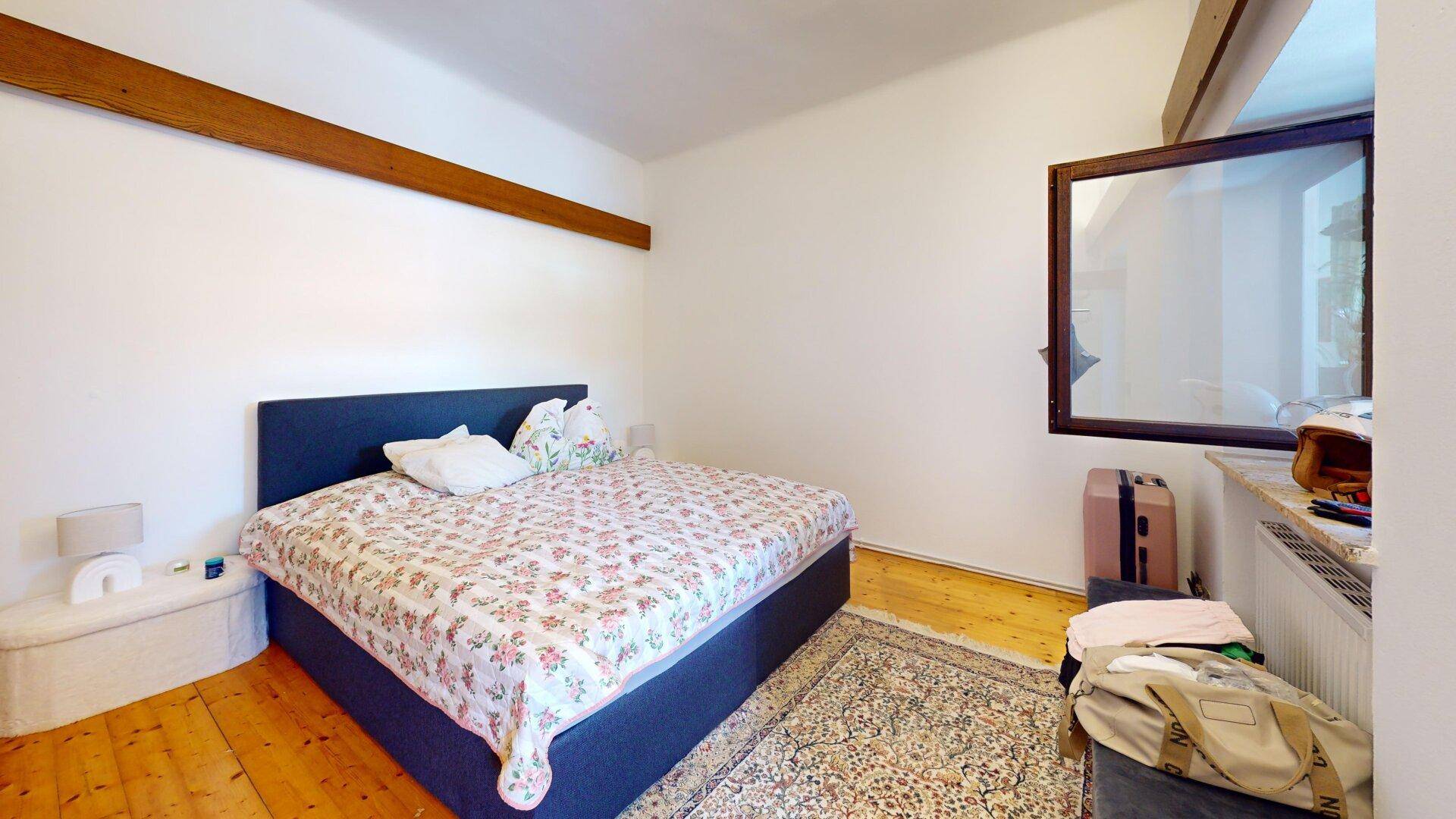 Schlafzimmer mit Holzboden, Doppelbett und Teppich, hell und gemütlich eingerichtet.