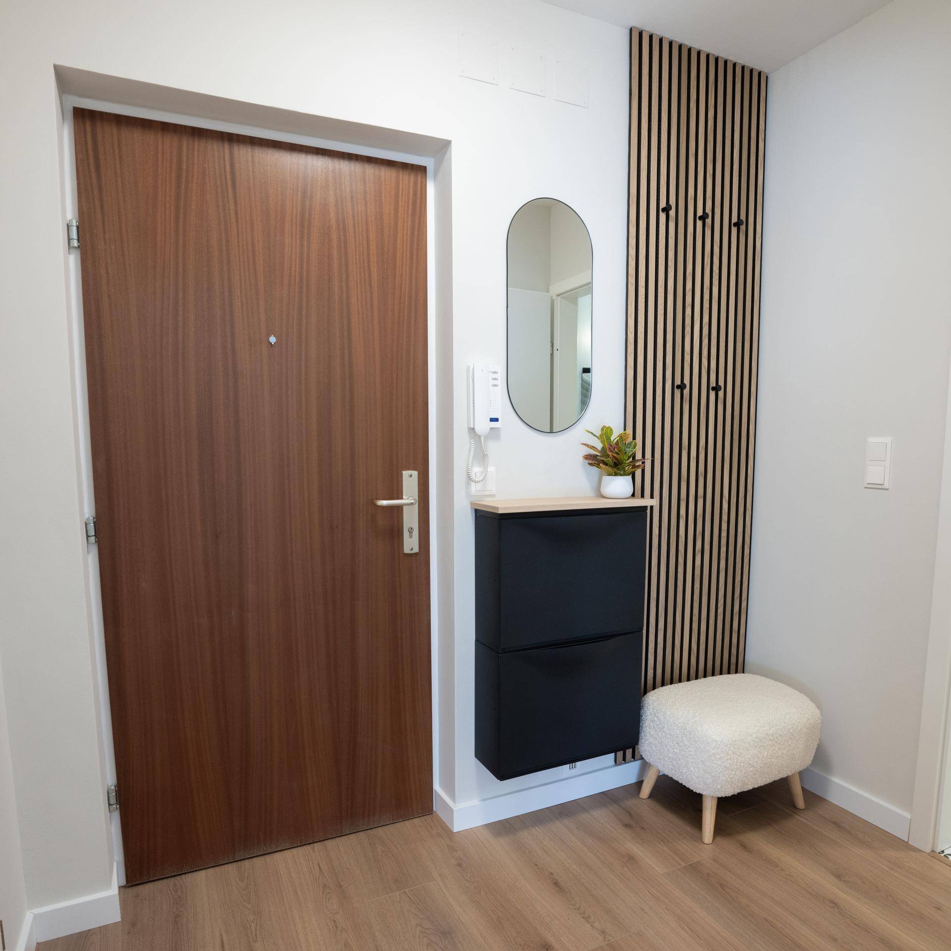 Moderner Eingangsbereich mit Holztür, Schuhschrank und dekorativer Holzvertäfelung.