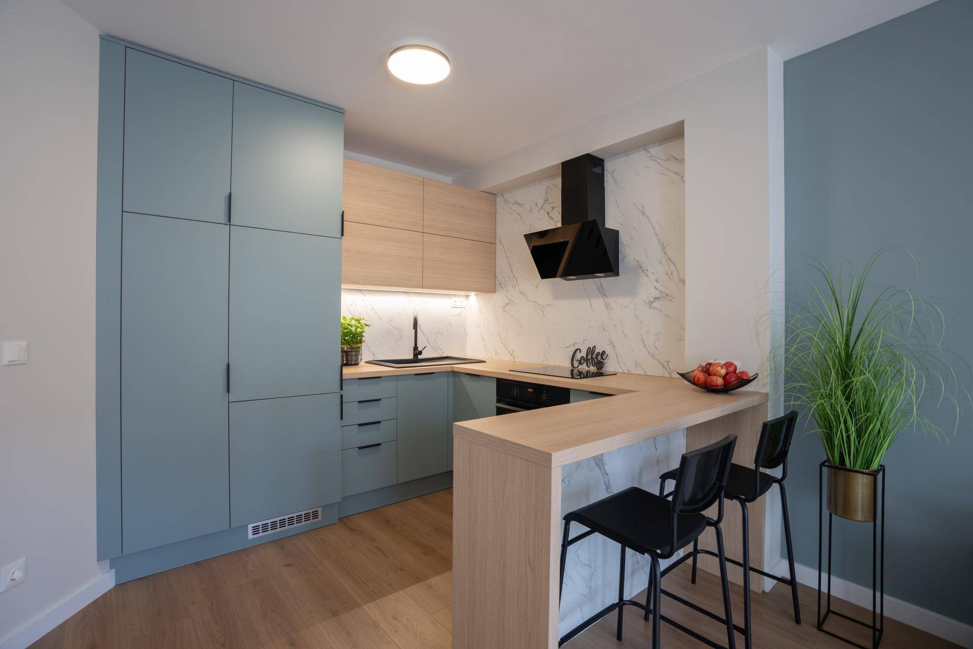Moderne Küche mit hellblauen und holzfarbenen Schränken, Kochinsel und Barhockern.