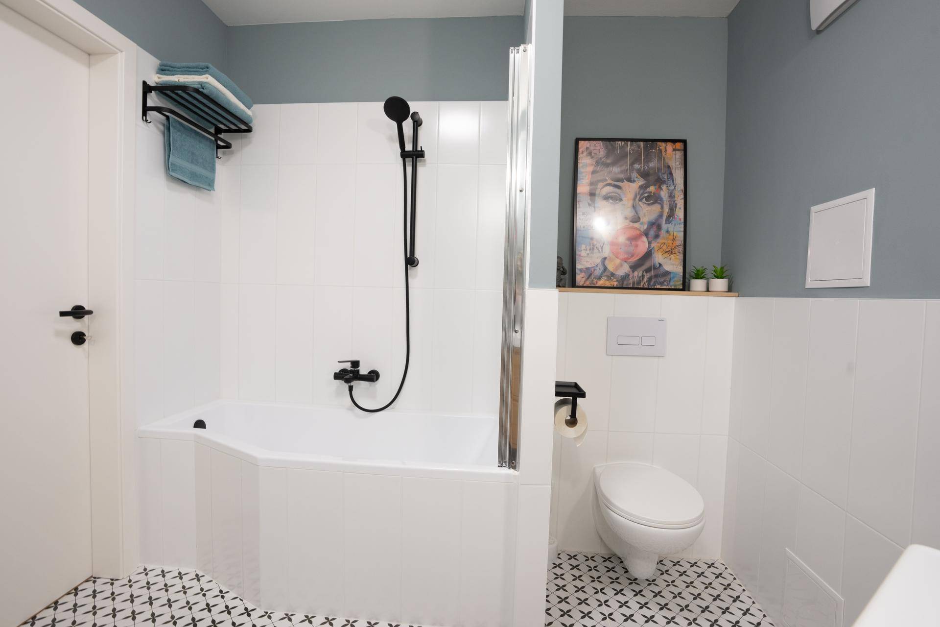 Badezimmer mit Badewanne, Duschvorrichtung und wandhängendem WC.