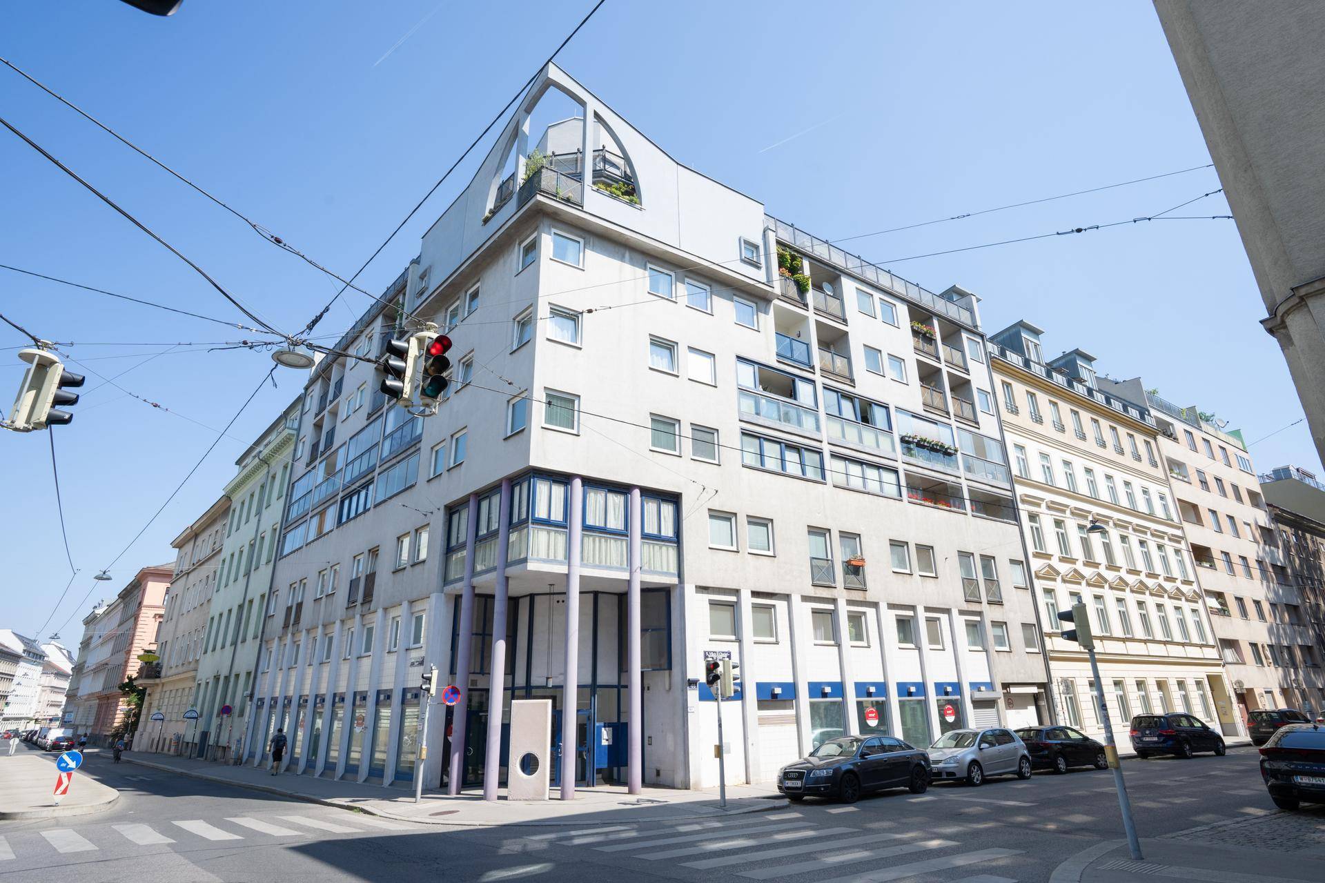 Modernes Mehrfamilienhaus mit vielen Fenstern und Balkonen in städtischer Umgebung.
