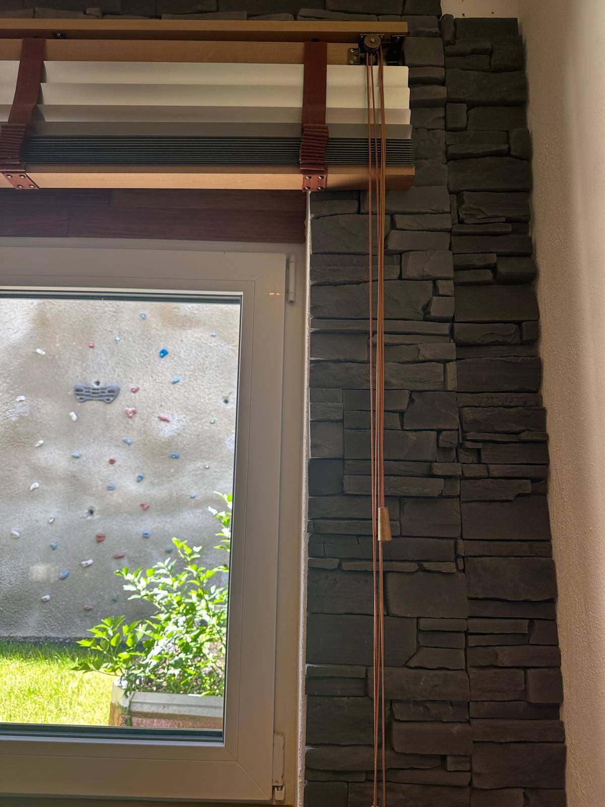Fenster mit Blick auf eine Kletterwand im Außenbereich, bringt Tageslicht in den Raum.