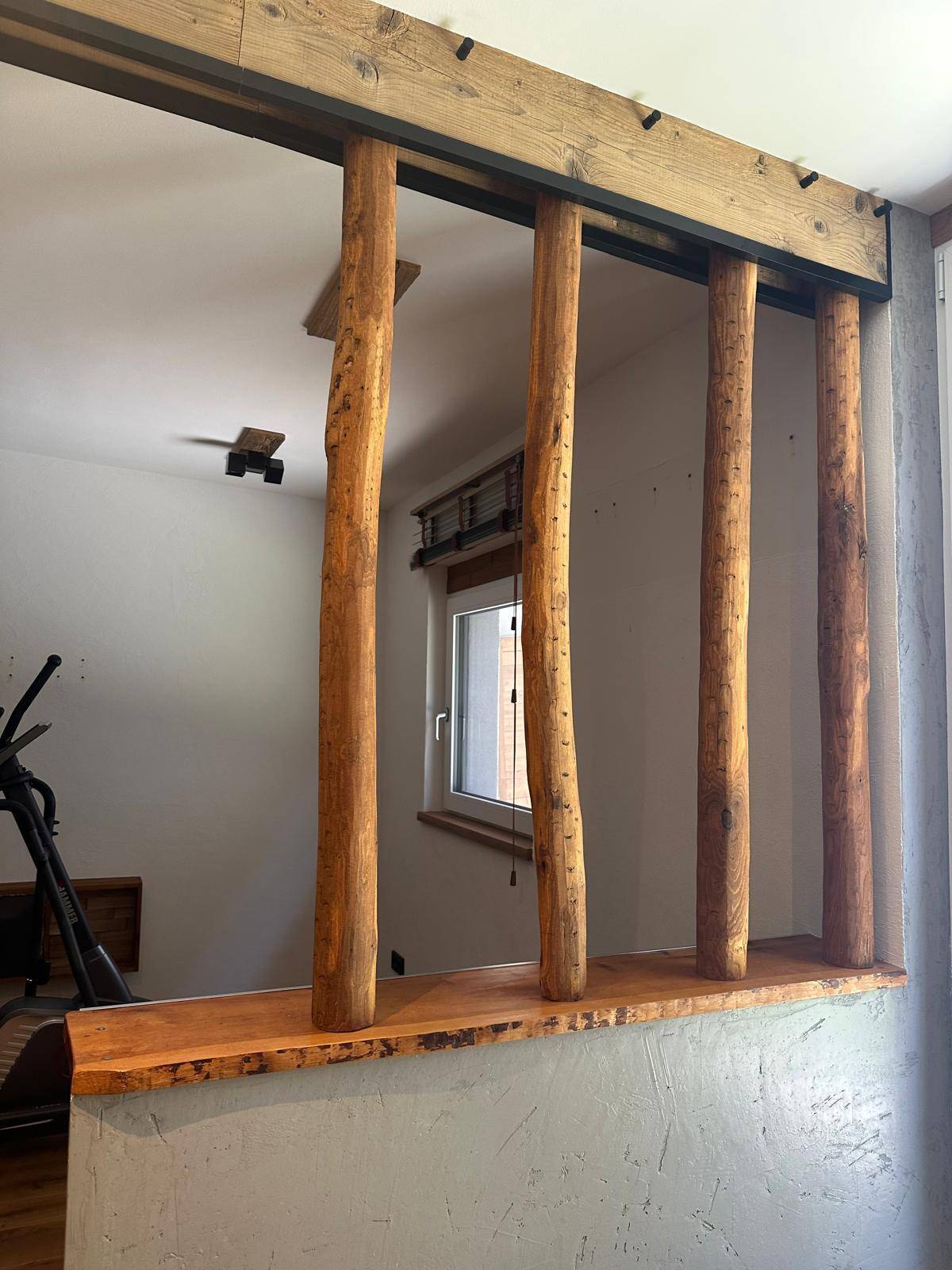 Detailansicht der Holzsäulen und des Fensters im Fitnessbereich, schafft eine natürliche Atmosphäre.