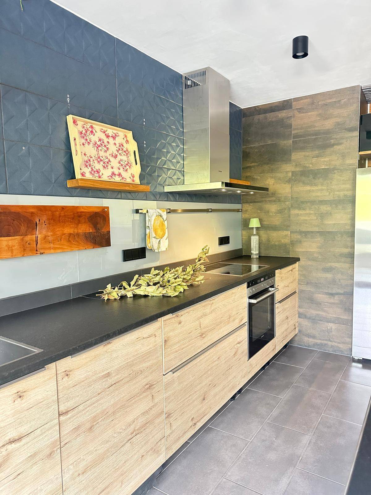 Küchenzeile mit integriertem Backofen, dunkler Arbeitsplatte und modernen Holzfronten.