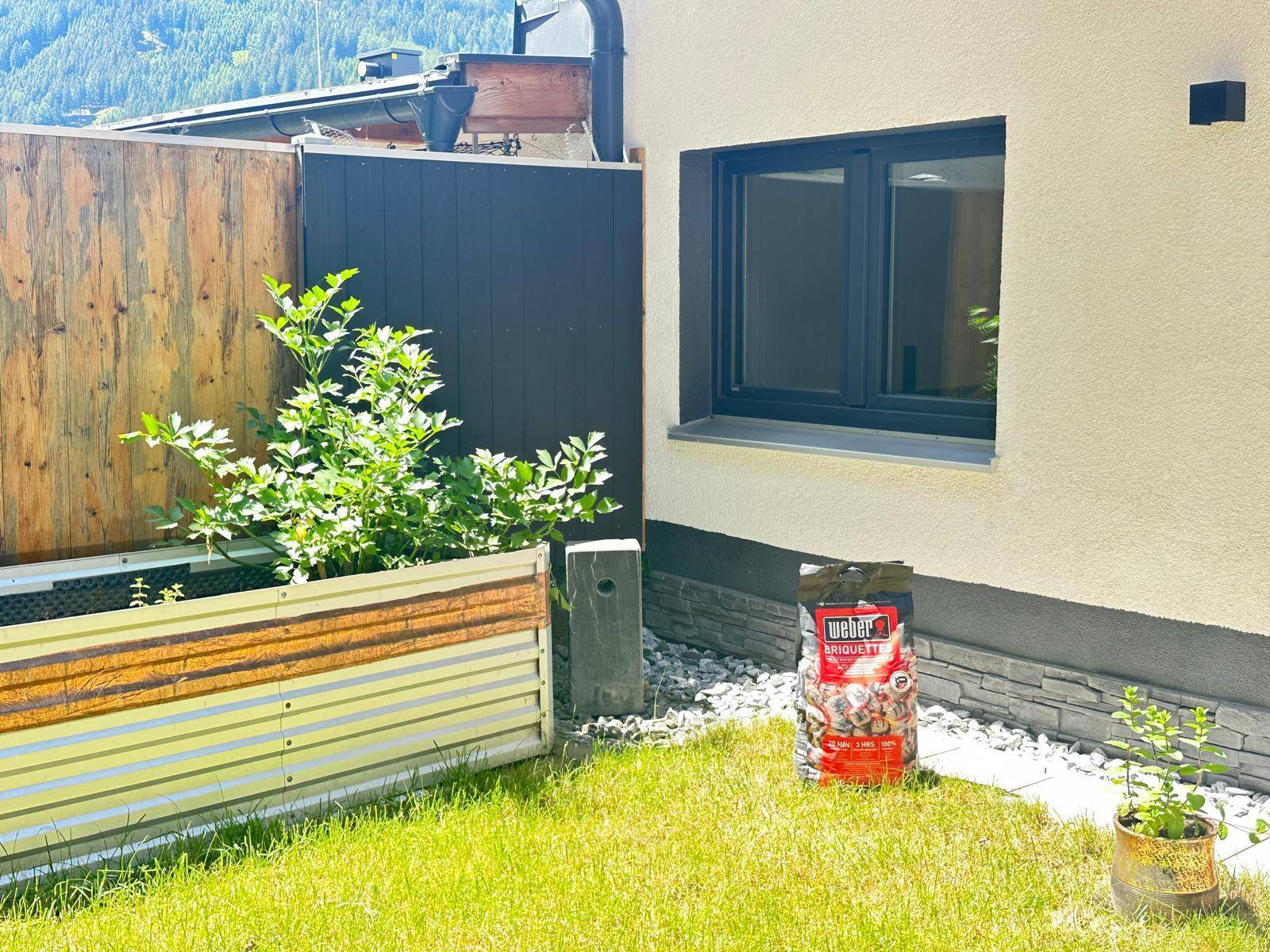 Gartenbereich mit Rasen, Hochbeet und Holzzaun, bietet Platz für Entspannung und Anbau.