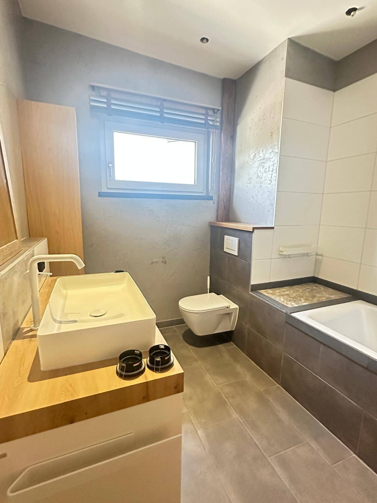 Modernes Badezimmer mit Waschbecken, WC und Badewanne, hell und funktional gestaltet.