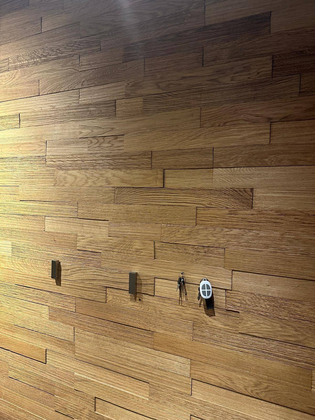 Detailaufnahme einer modernen Wandverkleidung aus Holzpaneelen, die eine warme Atmosphäre schafft.