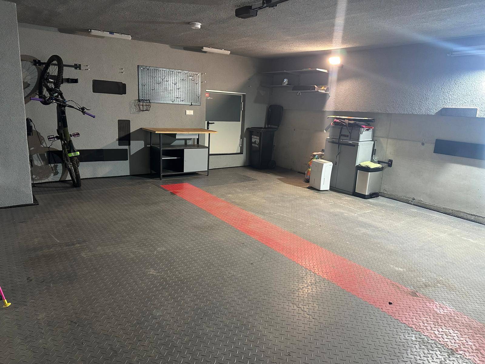 Gut ausgestattete Garage mit Werkbank, Regalen und Fahrradaufhängung, ideal für Hobby und Lagerung.