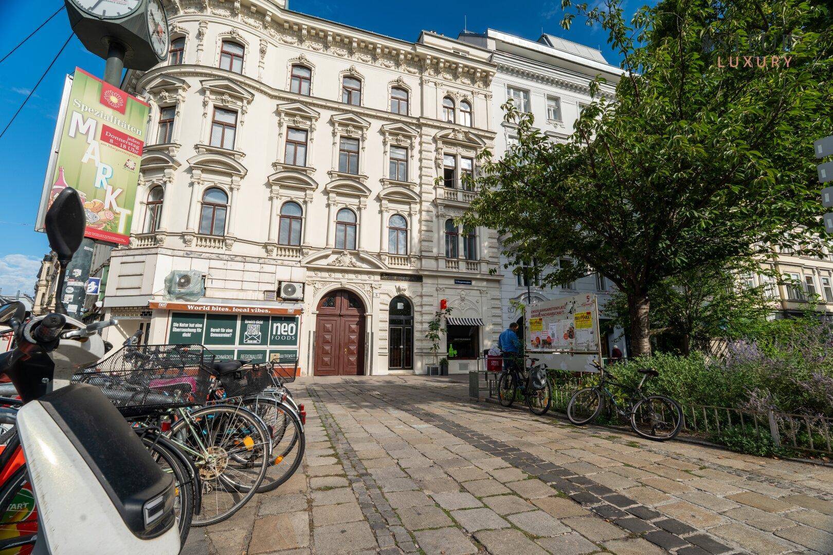 Elegantes Gebäude mit Geschäften im Erdgeschoss und gepflastertem Gehweg mit Fahrrädern.