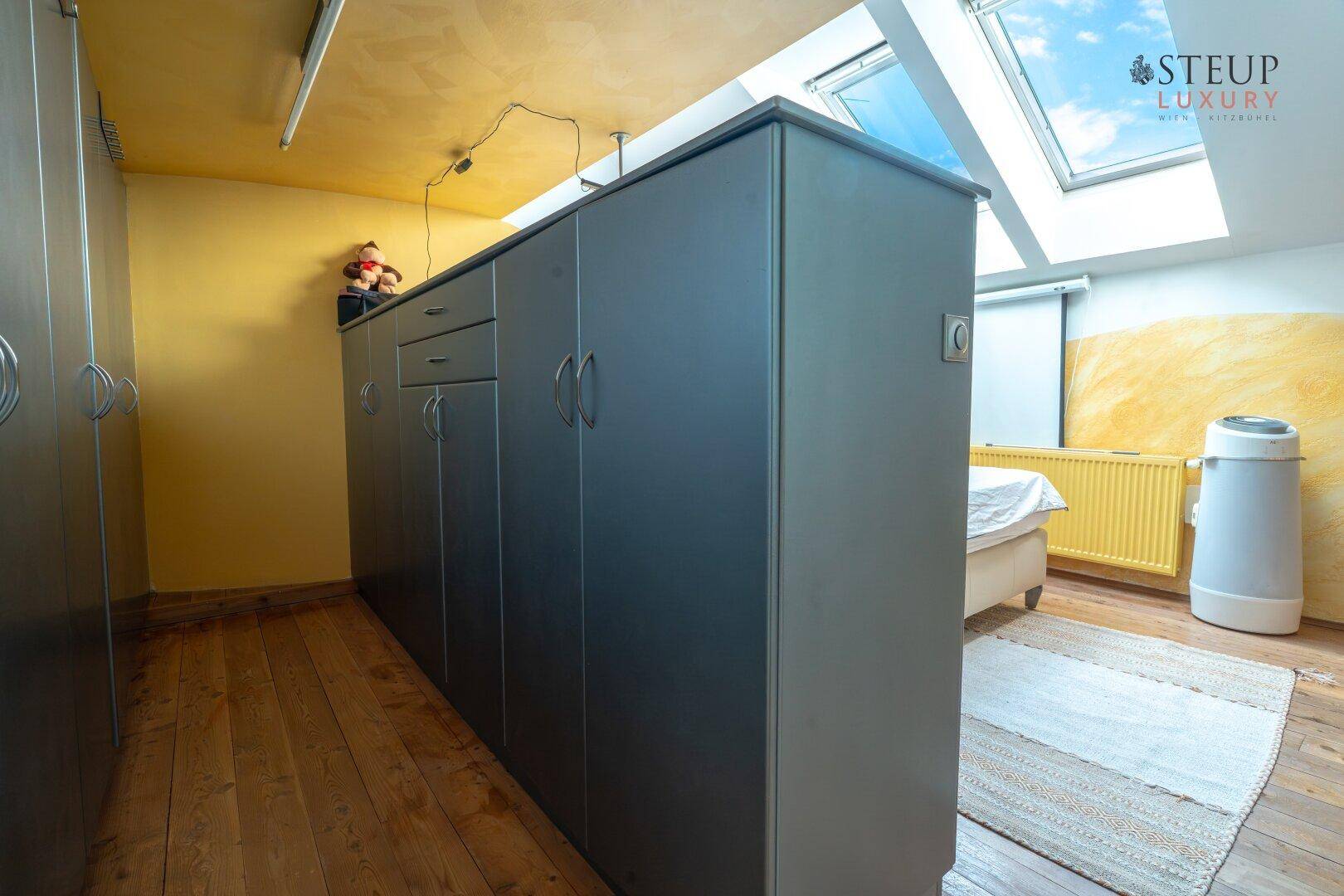 Schlafzimmer mit Einbauschränken, Holzboden und Dachfenster für viel Tageslicht.