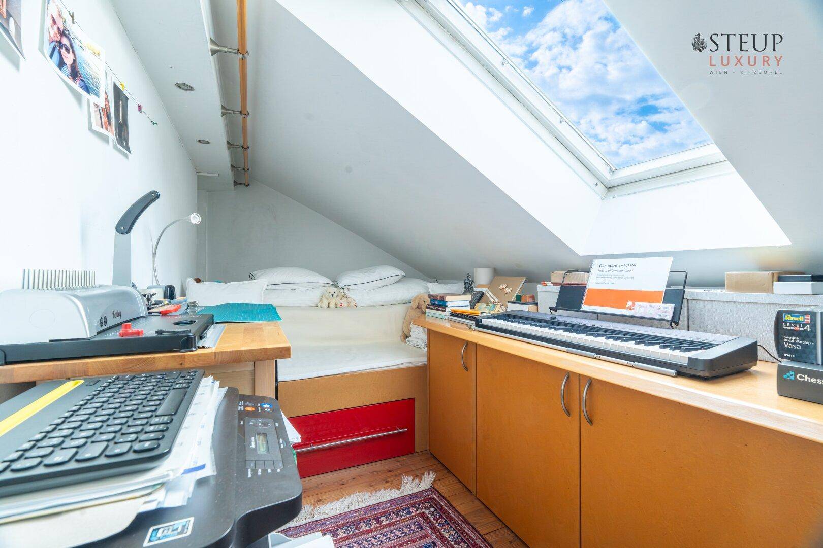 Gemütlicher Arbeitsbereich unter dem Dach mit großem Dachfenster und viel Tageslicht.