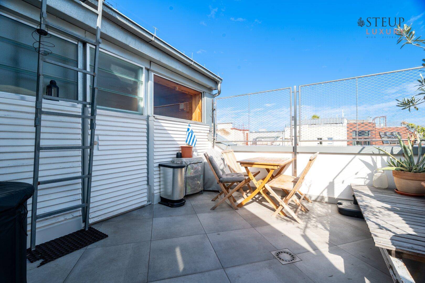 Dachterrasse mit Außenmöbeln und Blick auf die umliegenden Gebäude.