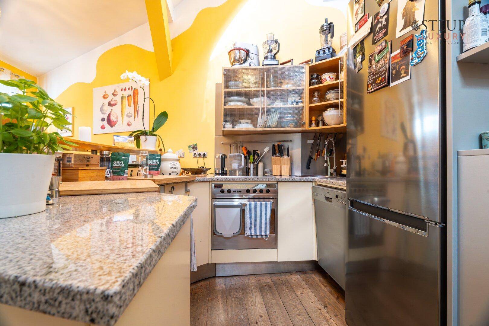 Moderne Küche mit Granitarbeitsplatte, Backofen, Geschirrspüler und Kühlschrank.