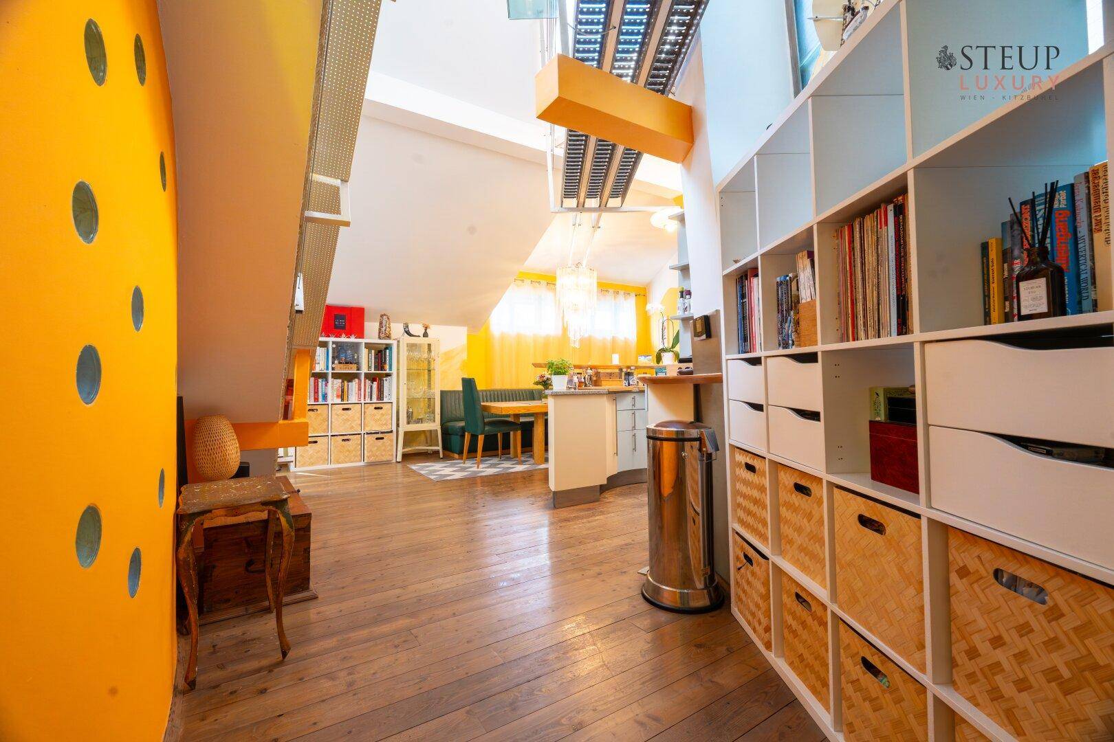 Heller Flur mit Holzboden, Bücherregalen und Blick auf den Essbereich.