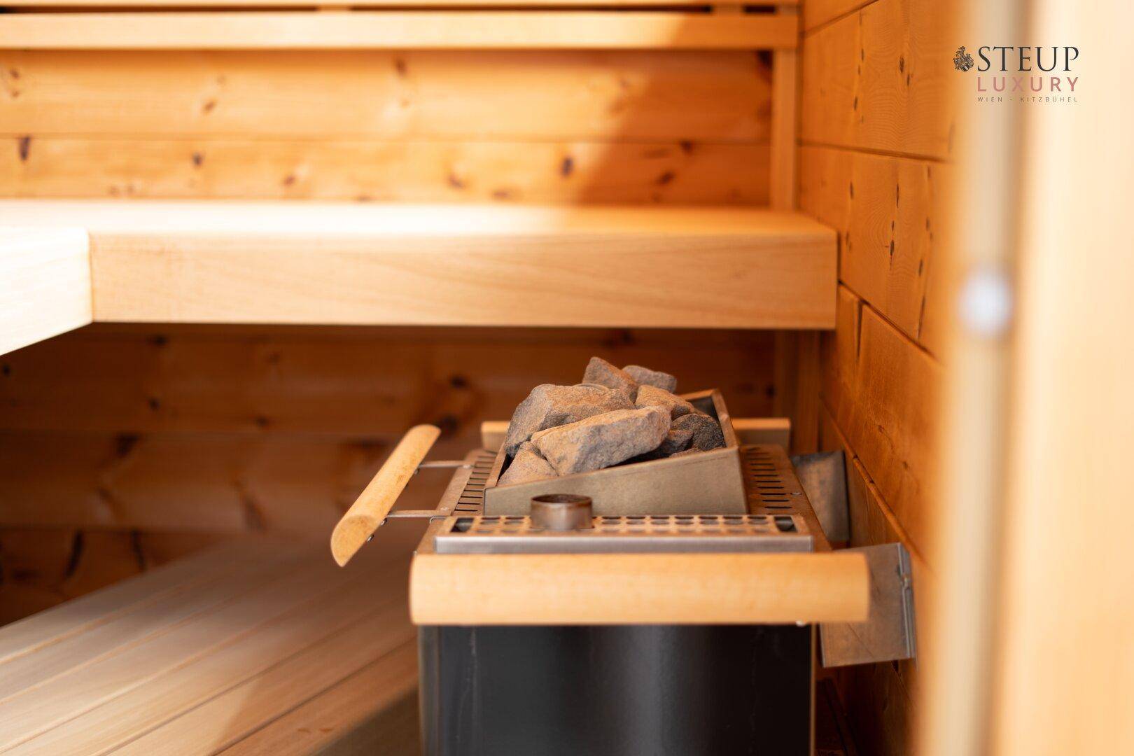Nahaufnahme des Saunaofens mit Steinen in einer holzvertäfelten Sauna.