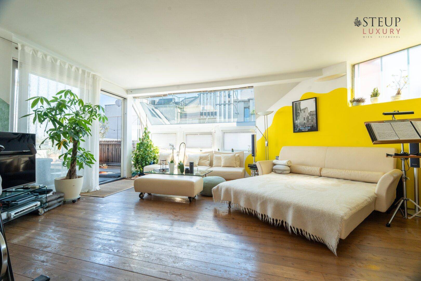 Geräumiges Wohnzimmer mit Schlafsofa, Holzboden und viel Tageslicht.