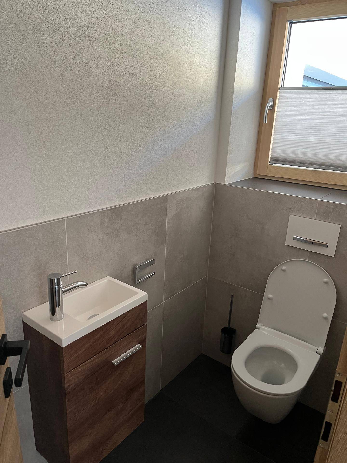 Modernes Gäste-WC mit kleinem Waschbecken, Wand-WC und Fenster.